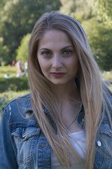 Beautiful blonde girl in denim jacket on nature background. Portrait close-up. Beautiful female face.