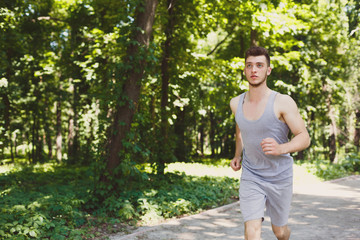Young man running in green park, copy space