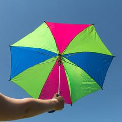 Multi-colored umbrella on blue sky background