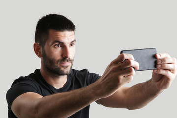 Portrait of young man taking selfie, studio shot on the grey background