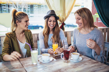 Female friends enjoying in conversation and drinking coffee in cafe