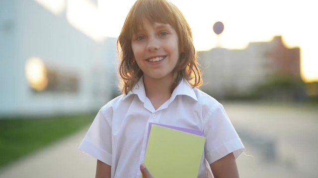 Close-up Portrait of European Boy. He Holds a Book in His Hands. His Smile is Beautiful. He Wears a School Uniform.