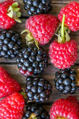 Raspberry and blackberry on a wooden background. Sweets and delicious summer berries.