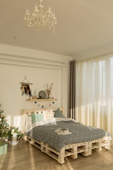 new year's bedroom interior. tree by the bed. bed with grey blanket. bedroom interior