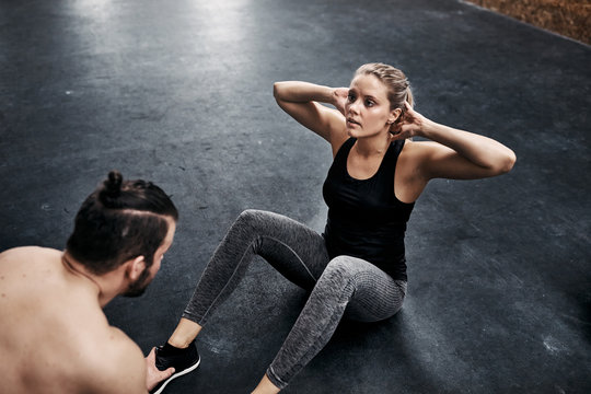 Fit young woman doing crunches with a gym partner