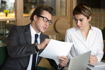 Businessman talking about contract terms and conditions, explaining company project to colleague, showing paper, office worker consulting with female colleague on business issue at corporate meeting