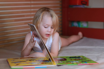 Petit garçon dans son lit regarde un livre