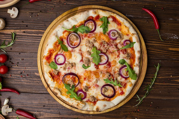 Minced meat tomato red onion pizza on a wood background