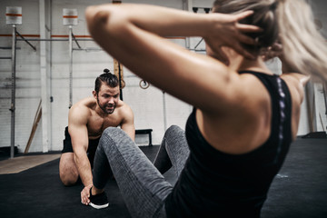 Fit woman doing sit ups with a male gym partner
