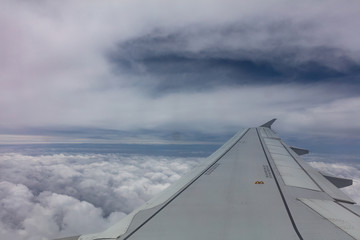 Fototapeta na wymiar Plane wing on cloudy sky background