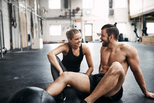 Two people sitting on a gym floor after working out