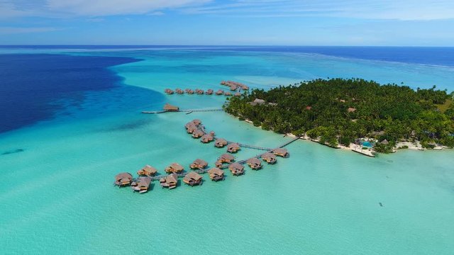 Aerial view of Motu Tautau, palm trees on little islets and turquoise water of blue lagoon, over water bungalows, tropical paradise of South Pacific Ocean - Tahaa island, seascape of French Polynesia