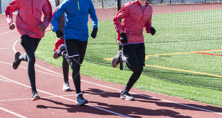 Four runners training in a group on a red track in winter