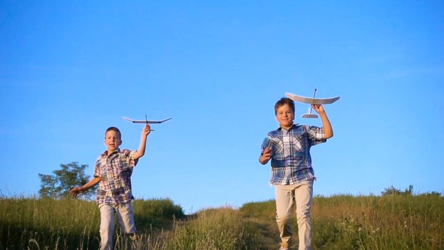 two boys running with his airplanes at the field