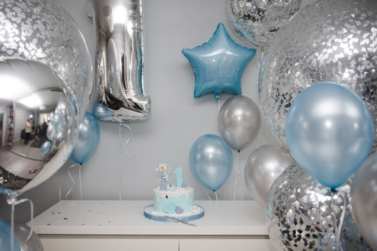 Colorful decoration of a first year birthday cake. Baby cake smash. Birthday cake for 1 year old boy. A lot of balls and cake. Birthday party in blue and silver.