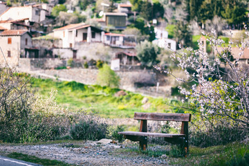 Beautiful spring landscape, a village in the mountains of Cyprus, blue sky, green hills, wooden bench and blossoming almond