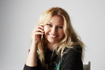 Beautiful smiling women using mobile phone against empty gray background.Studio shot