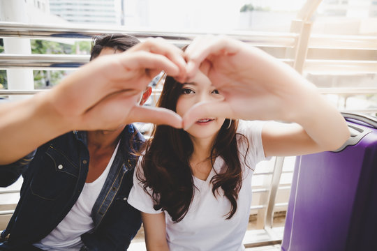 Portrait traveler couple. Handsome boyfriend and beautiful girlfriend is making symbol of love by using their hand and finger for making a shape of heart. They have honeymoon and special time together