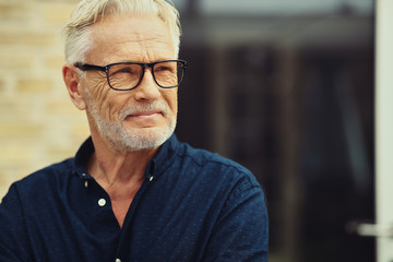 Content senior man standing outside in his yard