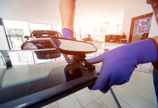 Automobile special workers replacing windscreen or windshield of a car in auto service station garage.