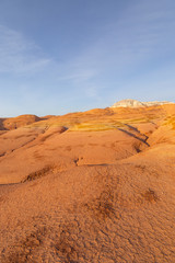 Fototapeta na wymiar Multicolored red, orange and yellow striped hills under a bright blue sky in Eastern Kazakhstan