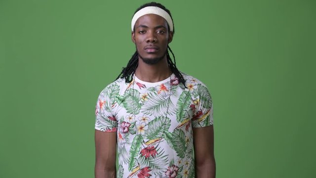 Young handsome African man with dreadlocks against green background