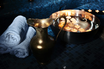 Scenery baths hammam, spa procedures. Copper jug, bowl with burning candles, white towels - obrazy, fototapety, plakaty