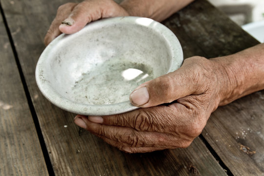 The poor old man's hands hold an empty bowl. The concept of hunger or poverty. Selective focus. Poverty in retirement.Homeless.  Alms
