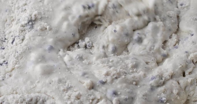 Mixing milk and dry blueberry muffin mix with a white spoon.