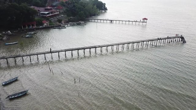 Aerial view of beautiful beach, old jetty with unidentified people, logo or brand during sunset. 