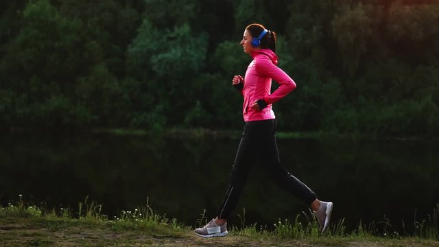 A morning jog in the Park near the pond in the Sunny rays of dawn, the girl is preparing to Mariano and lead a healthy lifestyle