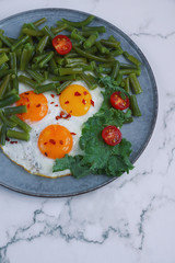 Fried eggs in with tomatoes, green beans, pepper and salad on a marble background, Healthy food, Fitness salad