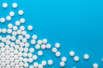 White pills on blue background, copy space