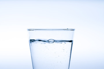 Glass of water with pouring from the bottle, studio shot