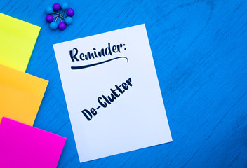 Reminder De-Clutter motivational concept on white paper and blue table flat lay in vintage tones