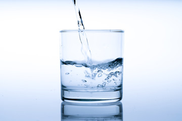 Glass of water with pouring from the bottle, studio shot