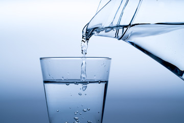 Glass of water with pouring from the bottle, studio shot
