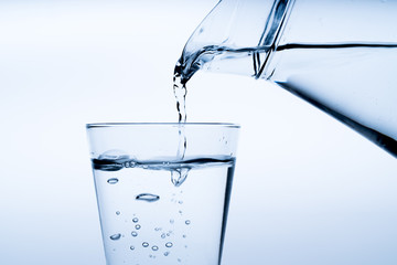 Glass of water with pouring from the bottle, studio shot