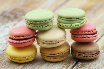 Stack of pistachio, chocolate and raspberry macaroons on wooden surface
