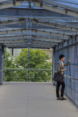 Fototapeta premium A man in a suit is standing on a bridge looking out into the distance