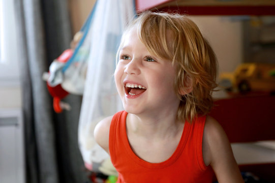 Petit gar&ccedil;on blond heureux rigole en regardant la t&eacute;l&eacute;