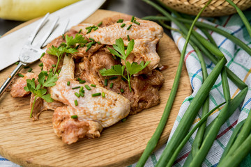 marinated raw chicken wings ready for grilling on a dark background. Raw chicken wings and vegetables