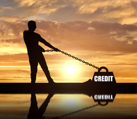 Silhouette of a man chained to a heavy load under the name of the credit. He drags him hard.