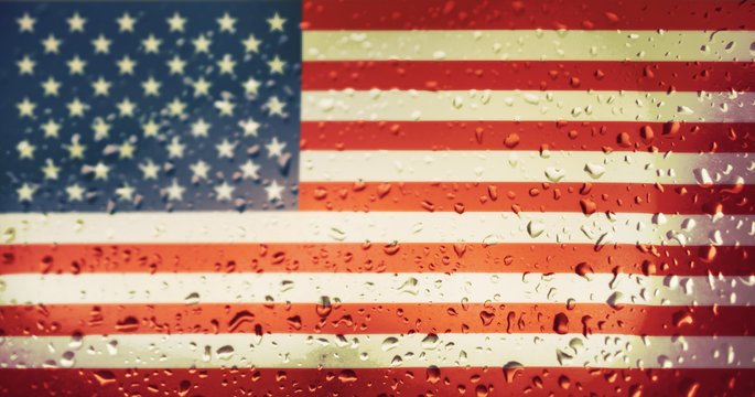 Texture of the USA flag on the glass with drops of rain at dawn.