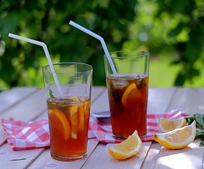 Cool drink, cold black tea with lemon, mint and ice in tall glasses. Summer concept