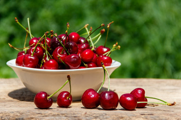 Naklejka na ściany i meble Bowl with fresh cherry on rustic wooden table outdoor