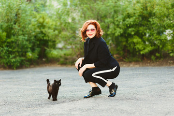 Naklejka na ściany i meble attractive woman in black suit and black cat outdoors