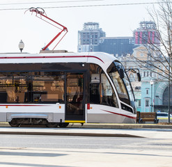 Modern tram moves at high speed through city streets.