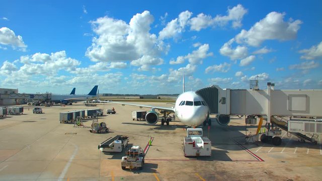 Generic Airport Concourse Exterior with Parked Airliners with Ground Support Vehicles Driving Around on a Sunny Day with White Clouds in a Blue Sky