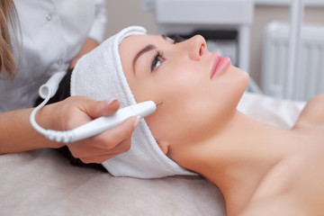 The cosmetologist makes the procedure treatment of Couperose of the facial skin of a beautiful, young woman in a beauty salon.Cosmetology and professional skin care.